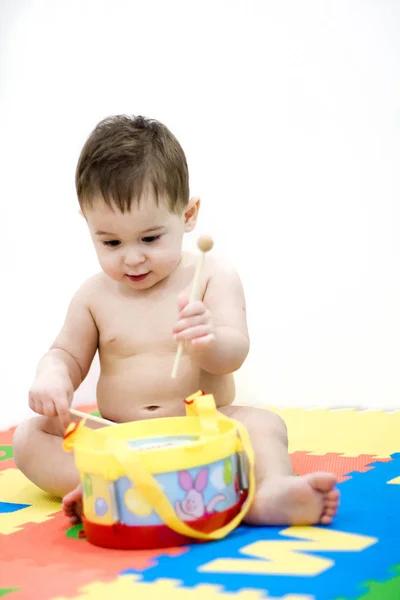 Baby barn spelar musikaliska leksak. pojken lär sig spela trumman. En glad leende 8 månader gamla baby flicka trummande. lärande leksaker i sitt hem. musikaliska leksaker på vit bakgrund — Stockfoto