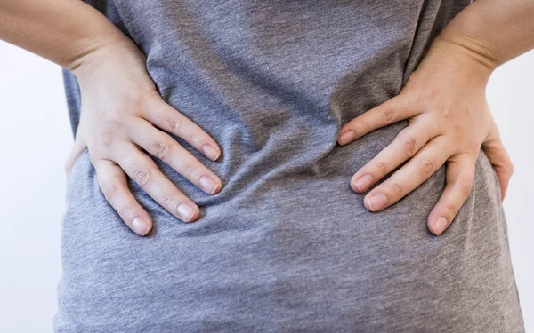 Atractiva persona femenina sufre de dolor de espalda. Todo sobre fondo blanco. lesión mujer estira dolor de espalda dolor de espalda, columna vertebral. causa de las largas horas de trabajo y la salud . — Foto de Stock