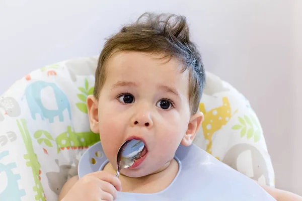 Mosolygó gyerek étkezés konyha. 1 év régi baba enni a saját leves. az első szilárd ételek, hogyan lehet megtanítani a gyermek enni, kanállal. aranyos baba eszik kanállal ebédre — Stock Fotó
