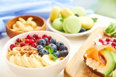 Kahvaltının üstü beyaz arka plan. Böğürtlenli yulaf ezmesi, tahta tepside tost, fındık, kahve.