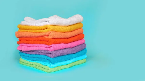 Pila di asciugamani puliti multicolore su uno sfondo blu — Foto Stock