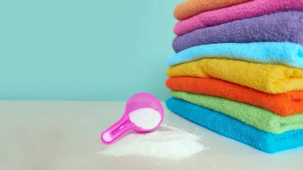 Pink plastic measuring vessel with washing powder, containers with detergent, stack terry towels — Stock Photo, Image