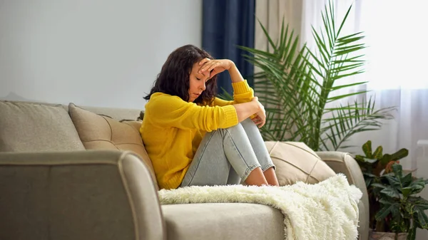 Depressive junge Frau sitzt zu Hause auf der Couch — Stockfoto