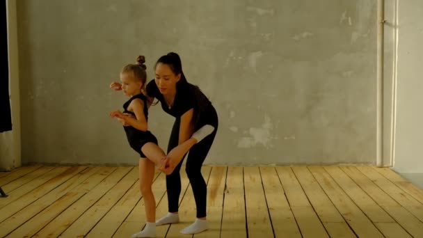 Professor de dança clássica em câmera lenta ensina alguns passos para seu jovem aluno que quer aprender a dançar e, no fundo, as outras meninas que ouvem . — Vídeo de Stock