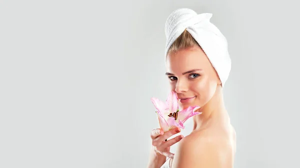 Young Woman with Clean Fresh Skin. Beautiful young girl. Photo of blonde girl with Lily on grey background. Skin care concept — ストック写真
