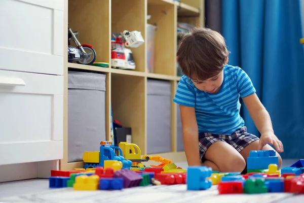 Маленький азиатский ребенок играет с большим количеством красочных пластиковых блоков в помещении, здание высокий замок . — стоковое фото