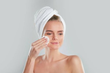 Sağlıklı bir kız pamukla makyajını temizliyor. Sünger gibi arka planda pamuklu ped sorunu olan bir kadın.