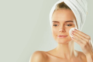 Sağlıklı bir kız pamukla makyajını temizliyor. Sünger gibi arka planda pamuklu ped sorunu olan bir kadın.