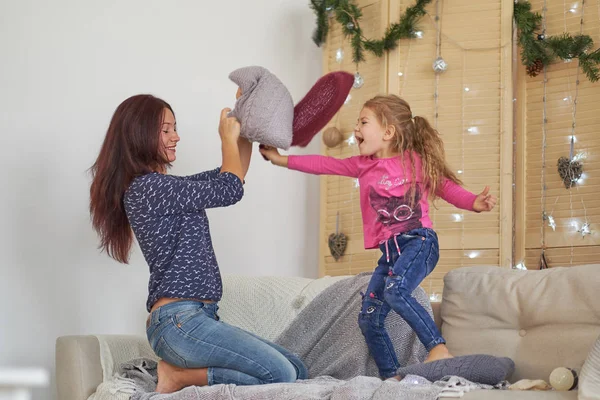 happy Mom and daughter having pillow fight at home. mother and little girl have fun together. Good time at home.