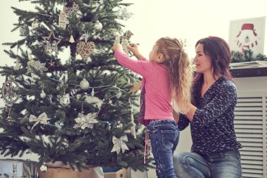 Anne ve kızı Noel ağacını süslüyor. Birlikte iyi eğlenceler. Evde iyi vakit geçir..
