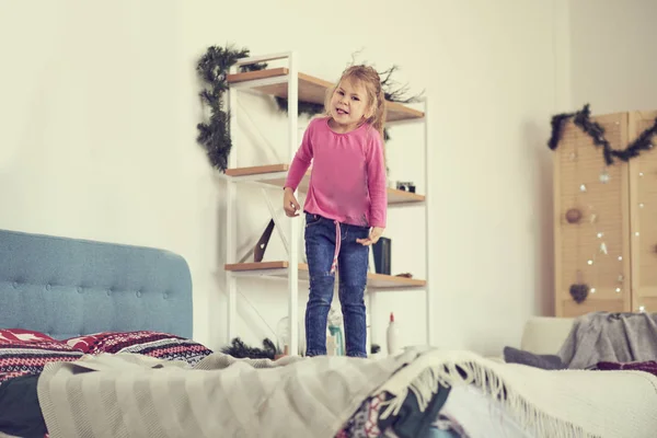 A happy girl in white dress having fun jumping on bed — Stock Photo, Image