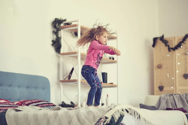 A happy girl in white dress having fun jumping on bed — Stock Photo, Image