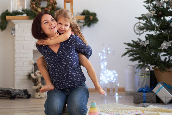 Мама и дочь играют вместе в элегантной рождественской комнате. Рождество с семьей
