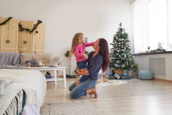 Maman et sa fille s'embrassent assis sur le sol sous le sapin de Noël. Le matin de Noël. Bon temps à la maison . — Photo