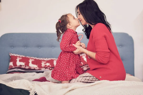 Maman et fille s'amusent ensemble. une femme en pull tricoté rouge chaud serre sa petite fille dans une robe rouge. valeurs familiales — Photo