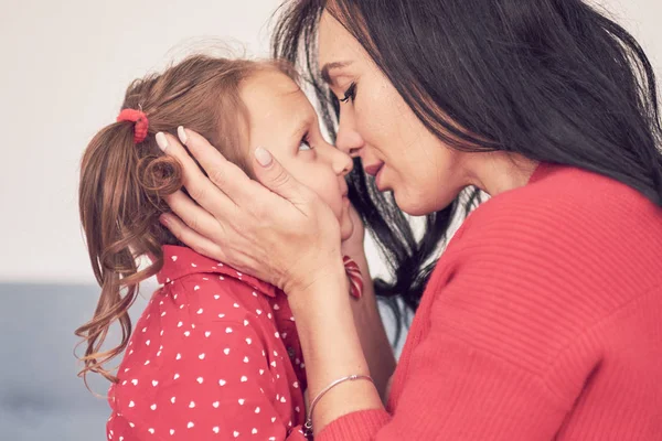 Maman et fille s'amusent ensemble. une femme en pull tricoté rouge chaud serre sa petite fille dans une robe rouge. valeurs familiales — Photo