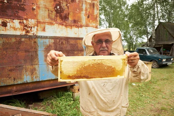 Viejo apicultor asiático. Coleccionista senior presentando panal de miel — Foto de Stock