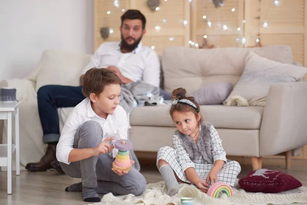 Dad and children have fun together, dad watches son and daughter play on the couch — Stock Photo, Image