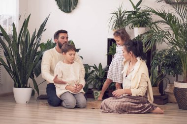 Evde oynayan kız ve oğlanla mutlu bir aile. Aile yerde oturuyor ve birlikte oynuyor..