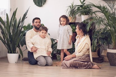 Evde oynayan kız ve oğlanla mutlu bir aile. Aile yerde oturuyor ve birlikte oynuyor..