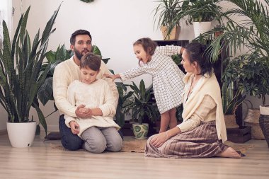 Evde oynayan kız ve oğlanla mutlu bir aile. Aile yerde oturuyor ve birlikte oynuyor..