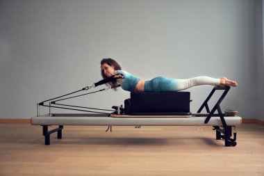 Leotard egzersiz pilates eğitimi. Atletik pilates yenilikçi egzersizleri. Pilates makinesi ekipmanı. Genç Asyalı kadın bir stüdyoda esneme sporu yapıyor.