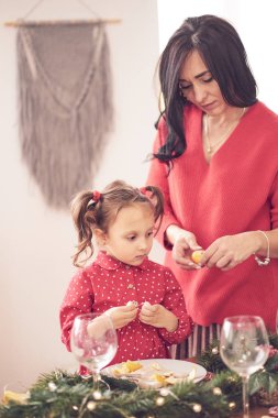 Anne ve kızı birlikte eğleniyorlar. Sıcak kırmızı örgü kazaklı bir kadın kırmızı elbiseli küçük kızına sarılıyor. aile değerleri