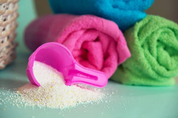 세탁 분말이 들어 있는 분홍색 플라스틱 측정 용기, 세제가 들어 있는 용기, 테리 타월을 쌓는다 — 스톡 사진