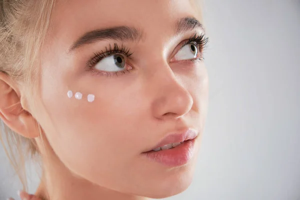 Retrato de mujer con cara sana aplicando crema cosmética debajo de los ojos — Foto de Stock