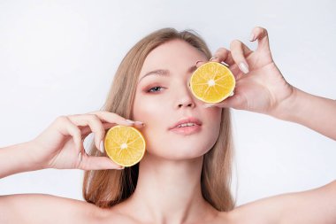 Portakal dilimleri ve yüz bakımı tutan güzel bir genç kadının portresi.