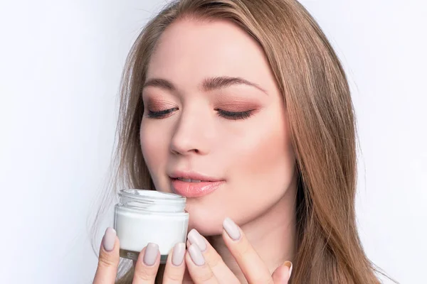 Beautiful girl holds a glass jar with luxury white cream in her hands. skin care in the winter.. Young woman with cosmetic cream. Healthy lifestyle concept. — 스톡 사진