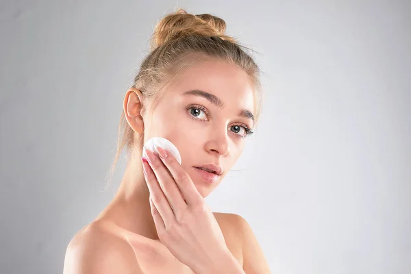 Ein gesundes frisches Mädchen entfernt ihr Gesicht mit einem Wattepad. Frau mit Schwamm mit Hintergrund Baumwollkissen Problemhaut — Stockfoto