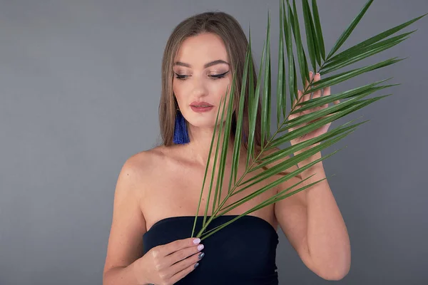 Portrait of young and beautiful woman with perfect smooth skin in tropical leaves. Concept of natural cosmetics and skincare. young beautiful woman with a palm leaf, clean skin