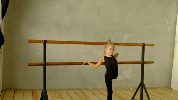 Slow motion teacher of classical dance teaches some steps to his young student who wants to learn how to dance and in the background the other little girls who listen. — Stock Video
