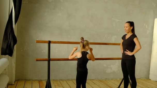 Professeur de danse classique au ralenti enseigne quelques pas à son jeune élève qui veut apprendre à danser et en arrière-plan les autres petites filles qui écoutent . — Video