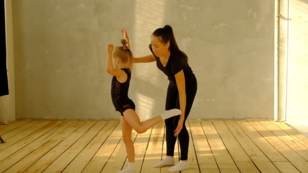 Professeur de danse classique au ralenti enseigne quelques pas à son jeune élève qui veut apprendre à danser et en arrière-plan les autres petites filles qui écoutent . — Video