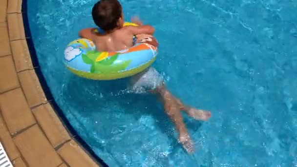 Αγόρι που επιπλέει σε έναν φουσκωτό κύκλο στην πισίνα, βίντεο αργής κίνησης — Αρχείο Βίντεο