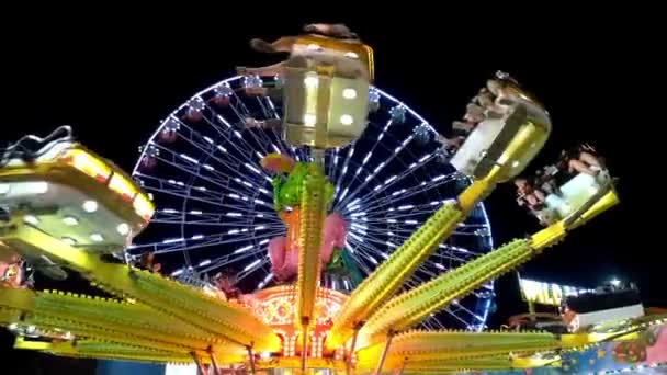Passeio de roda gigante brilhantemente iluminado girando à noite em um carnaval, parque de diversões, parque temático, feira, parque de emoção. — Vídeo de Stock