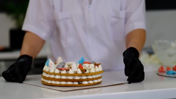 Mulher decora um bolo em sua cozinha. chef de pastelaria no trabalho — Vídeo de Stock