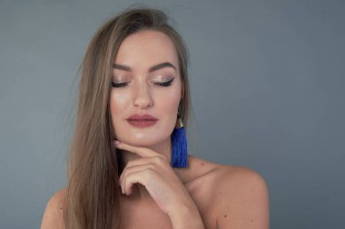 Genç ve güzel bir kadın çenesine eliyle dokunuyor. gömülü gözler, profesyonel makyaj..