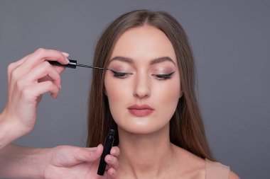 Makyöz kadının yüzüne siyah göz kalemi sürüyor. Makyaj sanatçısı tarafından makyaj yapan güzel bir kadın.