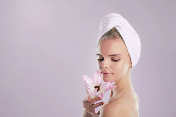 Woman with bath towel on head. Skin care concept. Young Woman with Clean Fresh Skin. Beautiful young girl. Photo of blonde girl with Lily on grey background. — 스톡 사진