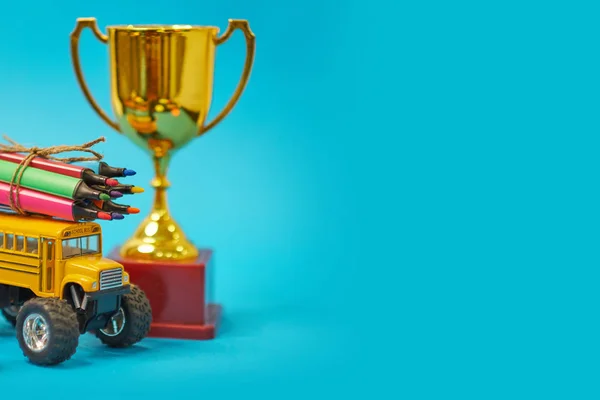 Gold winners trophy and Yellow School bus and felt-tip pens on the roof, back to school concept, yellow background, copy space. education. isolated on blue background — 스톡 사진