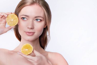Portakal dilimleri ve yüz bakımı tutan güzel bir genç kadının portresi.