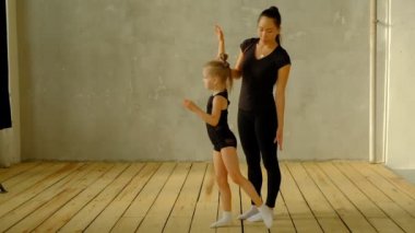 Klasik dansın yavaş çekim hocası, dans etmeyi öğrenmek isteyen genç öğrencisine bazı adımlar öğretiyor. Arka planda da ise, dans dinleyen diğer küçük kızlara..