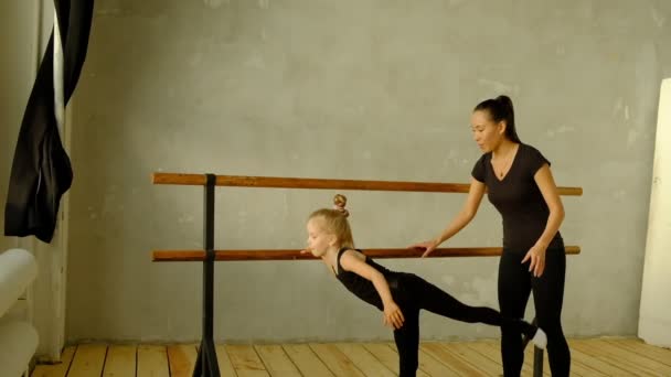 Slow motion docent klassieke dans leert enkele stappen aan zijn jonge student die wil leren dansen en op de achtergrond de andere kleine meisjes die luisteren. — Stockvideo