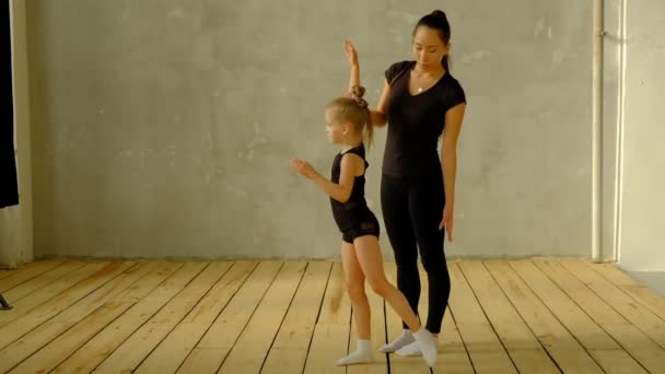 Slow motion teacher of classical dance teaches some steps to his young student who wants to learn how to dance and in the background the other little girls who listen. — ストック動画