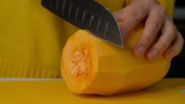 La mujer cocinera corta la calabaza en pedazos pequeños. calabaza en un tablero de madera, ingredientes para cocinar sopa de crema de calabaza . — Vídeos de Stock