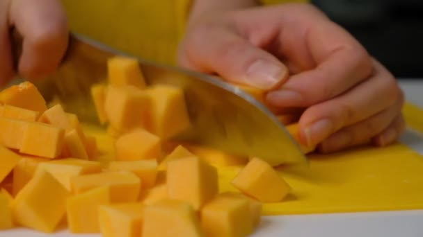 La mujer cocinera corta la calabaza en pedazos pequeños. calabaza en un tablero de madera, ingredientes para cocinar sopa de crema de calabaza . — Vídeos de Stock