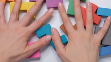 Kadın elleri beyaz bir masadan tahta küpleri temizler, düz yatak, çerçeve küpleri, çocuk eğitimi kavramı